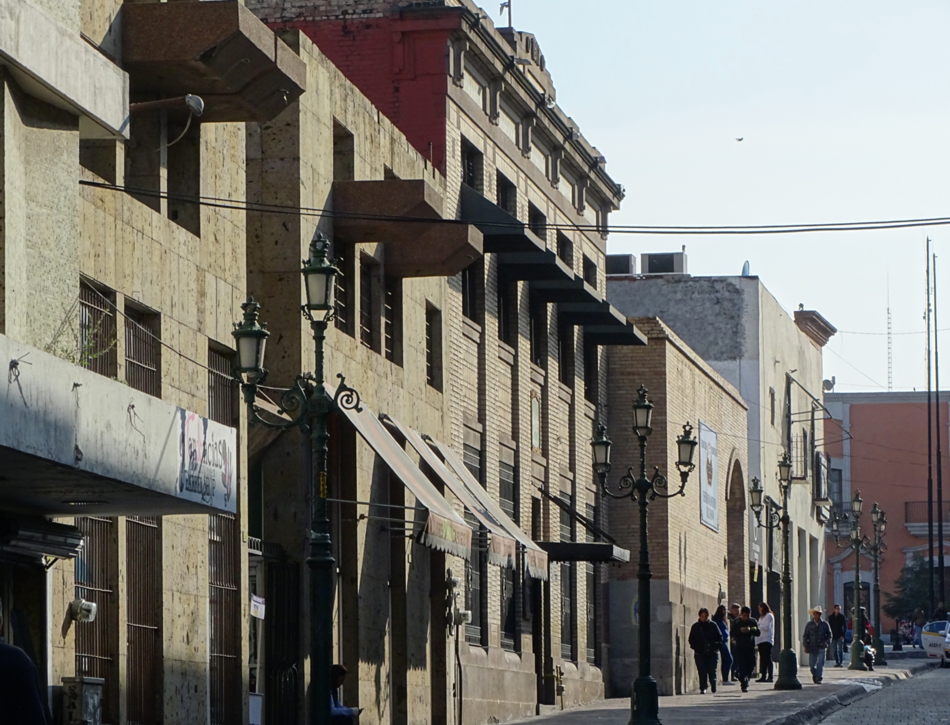Calle del Centro histórico de Saltillo, con faroles de hierro, toldos y gente en la banqueta.